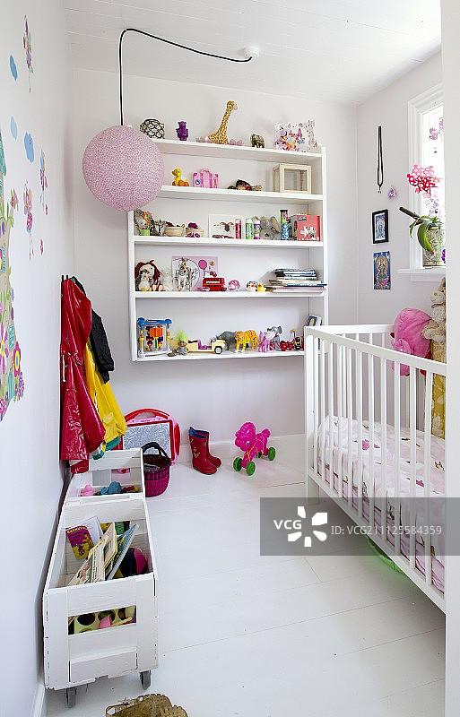 带白色婴儿床、壁挂式搁板和木箱玩具的儿童卧室图片素材