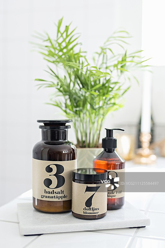 浴室白色瓷砖上的复古瓶装浴盐图片素材