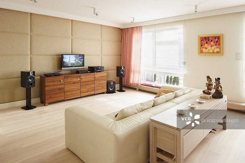 奶油色皮沙发，对面是纯平电视；前景是餐具柜上的民族饰品图片素材