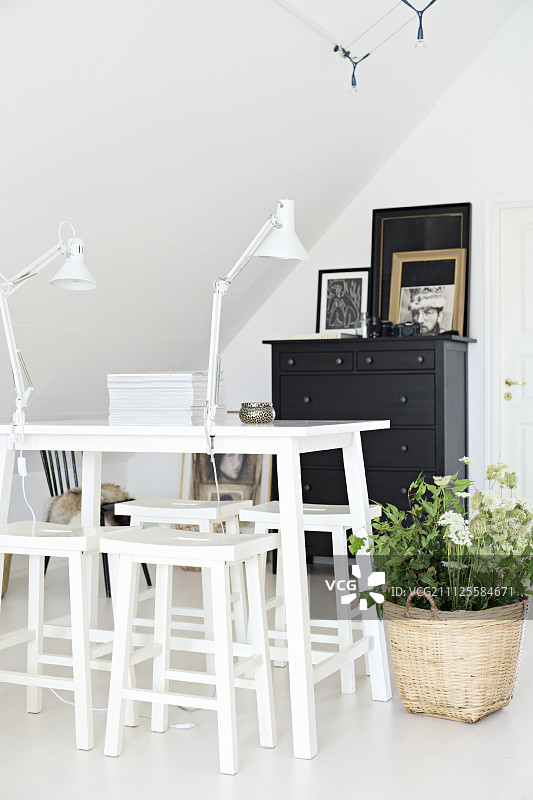 阁楼房间地板上，漆成白色的桌子、凳子和篮子里的植物图片素材