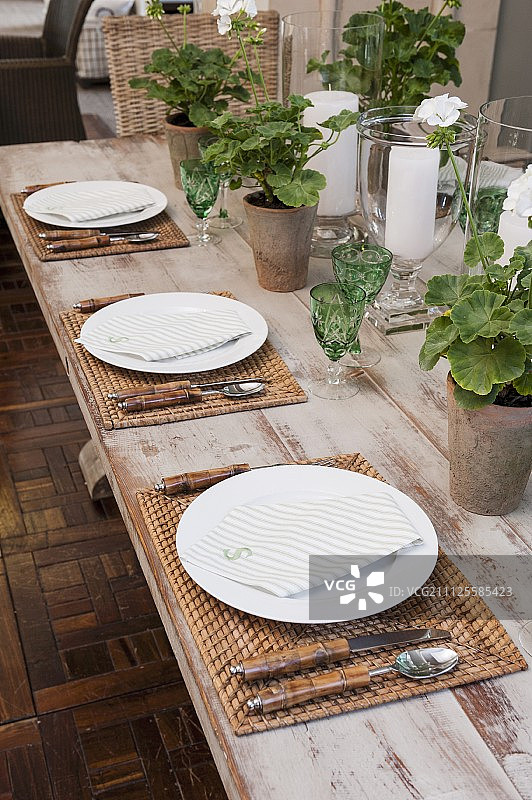 绿色水晶杯、编织餐垫和赤陶盆天竺葵餐桌图片素材