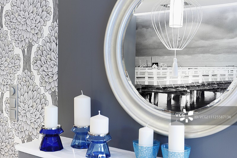 照片墙：圆形镜子中倒映出的旧木码头，前景是蓝色玻璃烛台图片素材
