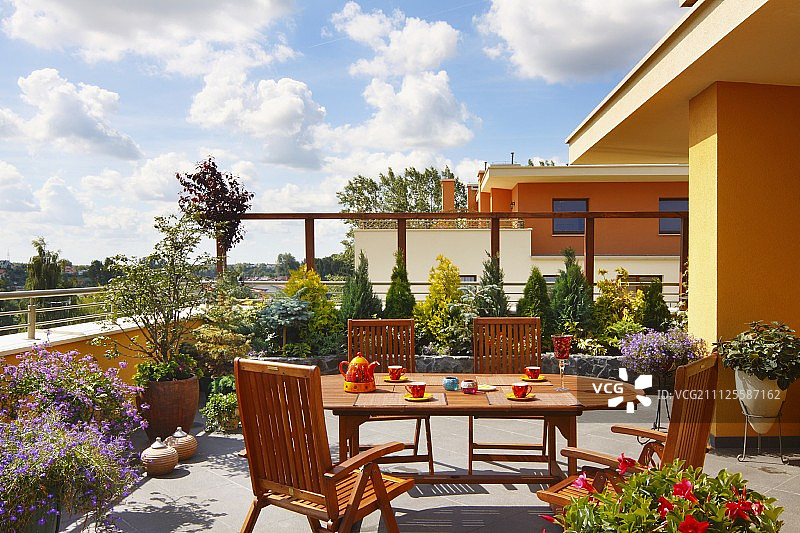 现代住宅区阳光屋顶露台上的柚木椭圆形桌椅图片素材