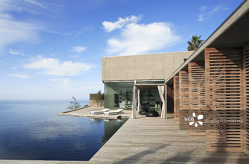 带开放式木百叶门、环绕露台和海景无边泳池的现代住宅图片素材