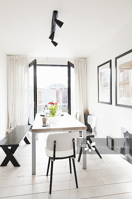 现代餐桌，搭配黑白椅子和长凳，落地窗外城市景观图片素材