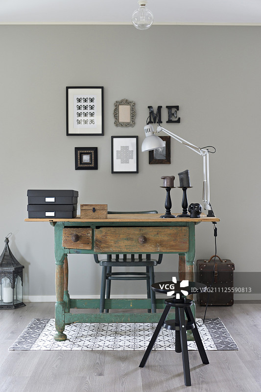 黑色旋转凳和带有剥落油漆的乡村木桌靠在浅灰色墙壁上图片素材