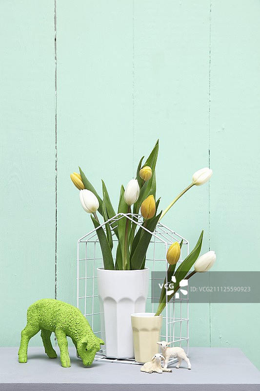 柔和色调的复活节装饰摆件：烧杯中的郁金香和羔羊饰品图片素材