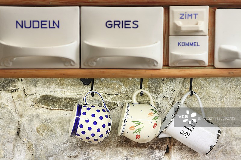 挂在石墙上的中国勺子和复古杯子标签图片素材