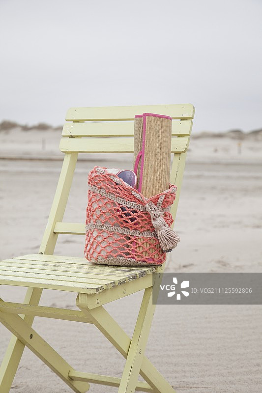 沙滩木椅上钩针编织沙滩包里的草席图片素材
