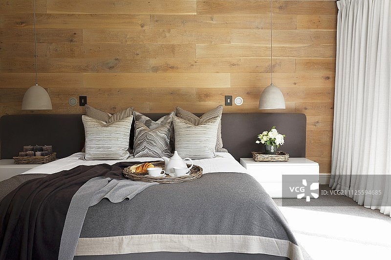 卧室：灰色床品双人床，软包床头板和靠垫，木墙图片素材