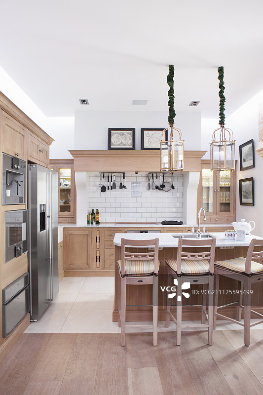 现代乡村风格开放式厨房中的吧台凳和浅色木质柜台图片素材