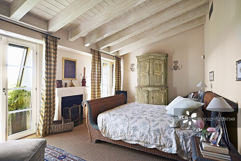 乡村卧室中带白色木天花板的藤编雪橇床图片素材