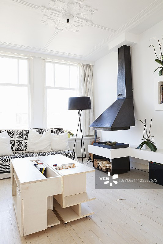 客厅里浅色木质定制咖啡桌和带罩的开放式壁炉图片素材