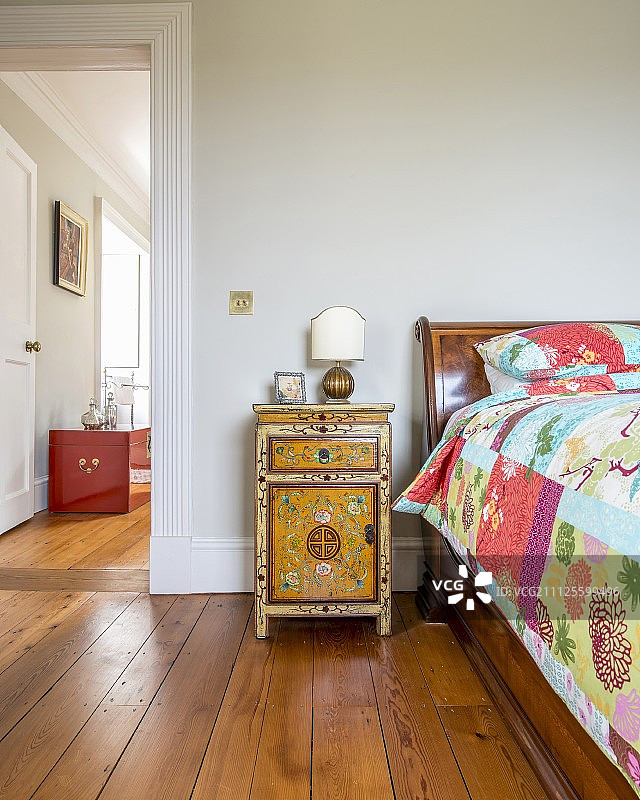 东方风格橱柜、拼布被古董床和红色行李箱图片素材