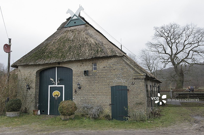 冬季景观中带茅草屋顶和深蓝色门的旧砖谷仓图片素材
