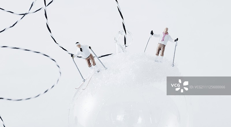 用滑雪微型小雕像装饰的白色圣诞节装饰球图片素材