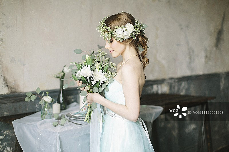 手捧花束，头戴花环的童话新娘在复古内饰中图片素材