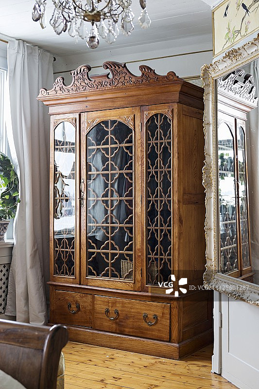 传统内饰中带玻璃门板的雕刻古董木柜图片素材