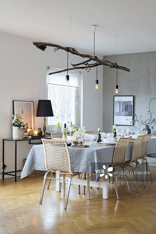 圣诞节餐桌，配有斯堪的纳维亚藤椅和树枝悬挂的灯饰图片素材