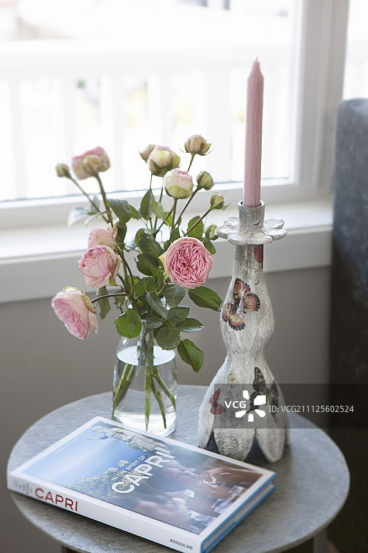 玫瑰花瓶、卡普里岛书籍和边桌上的烛台图片素材