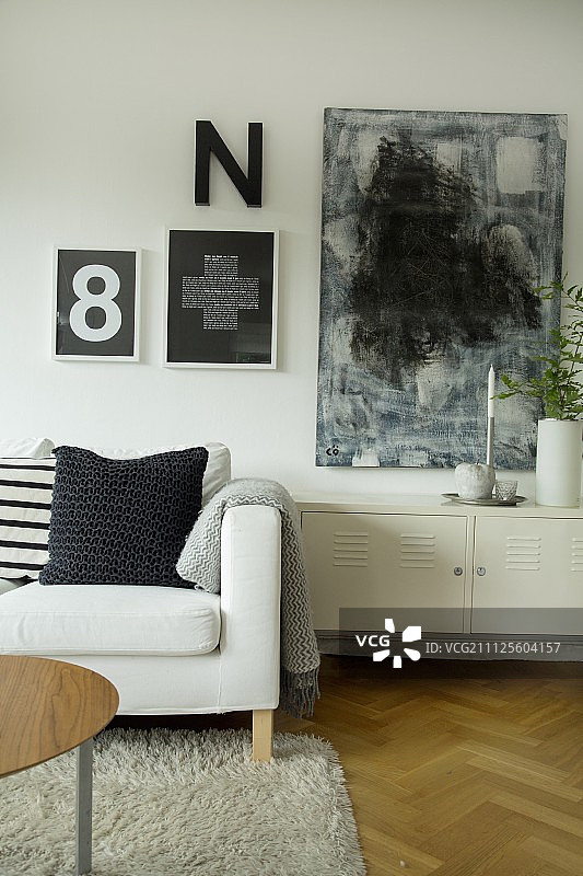 沙发靠垫与矮柜，墙上黑白抽象画图片素材