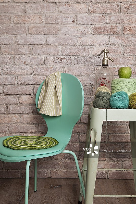 绿松石椅子上的钩针坐垫，砖墙背景上的钩针纱线和苏打虹吸管图片素材