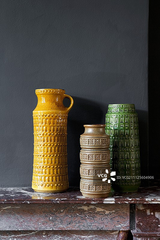 黑色墙壁壁炉架上的彩色复古花瓶合集图片素材