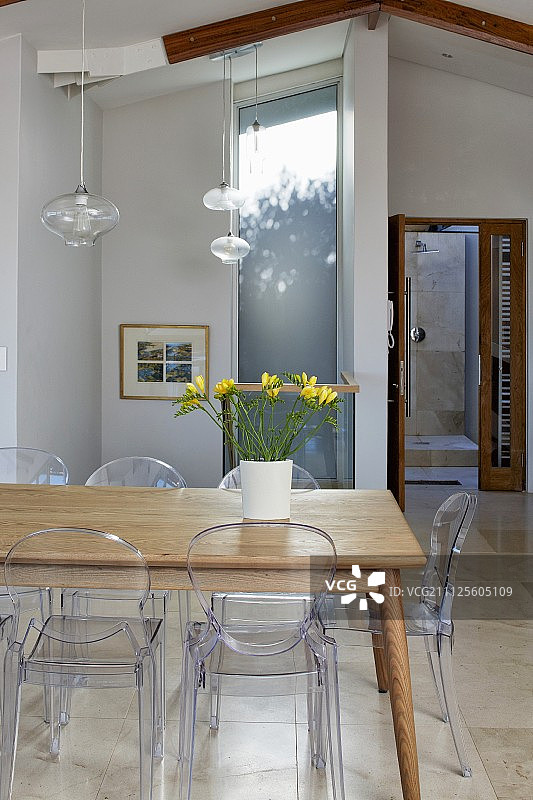 现代室内木桌上的黄色小苍兰花瓶与玻璃灯罩吊灯图片素材