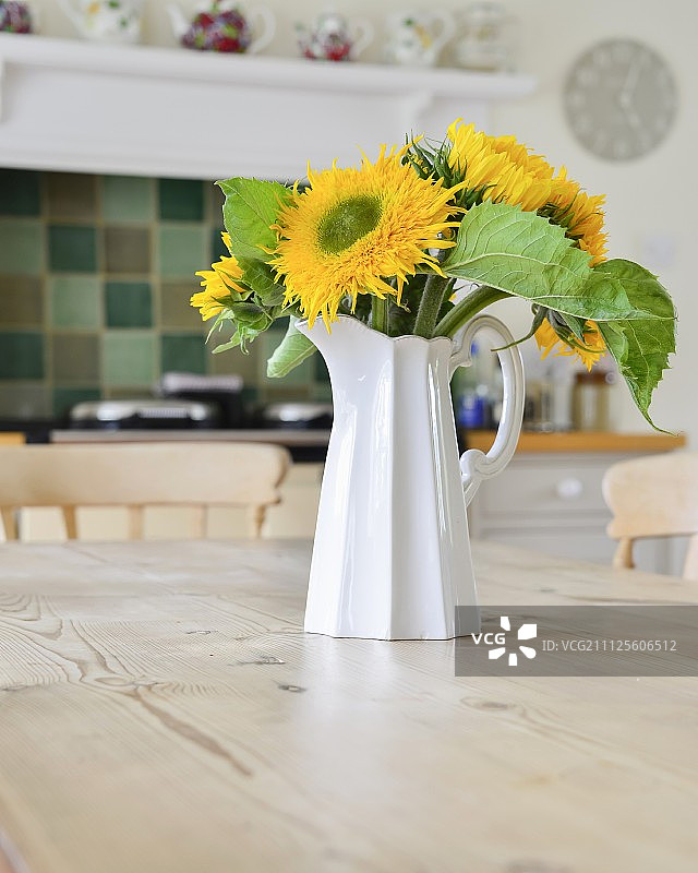 乡村别墅厨房木桌上的向日葵白色水罐图片素材