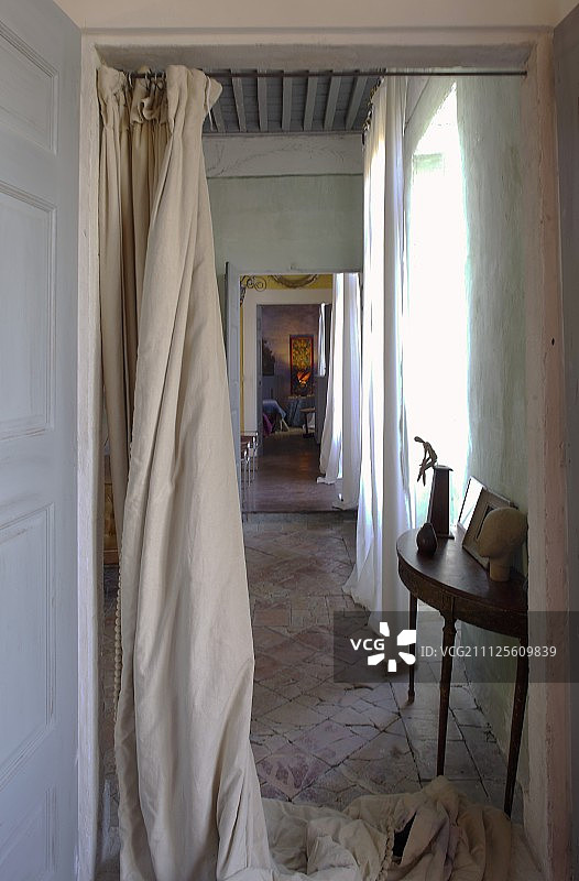 透过落地窗帘看复古石地板上的精致控制台图片素材