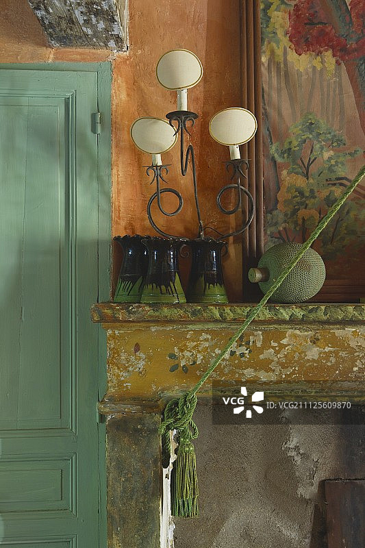 花瓶和复古台灯在剥落油漆的壁炉架上图片素材