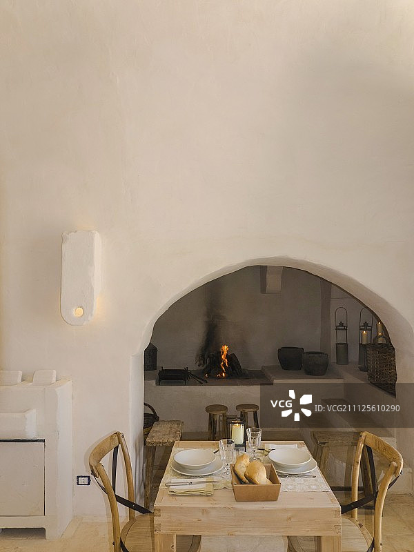 乡村普利亚特鲁洛拱形壁龛前带开放式壁炉的餐桌图片素材