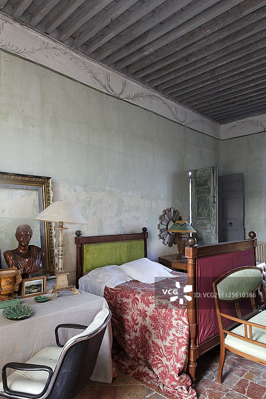 地中海卧室内的仿古雪橇床、图案床罩、桌子和复古转椅图片素材