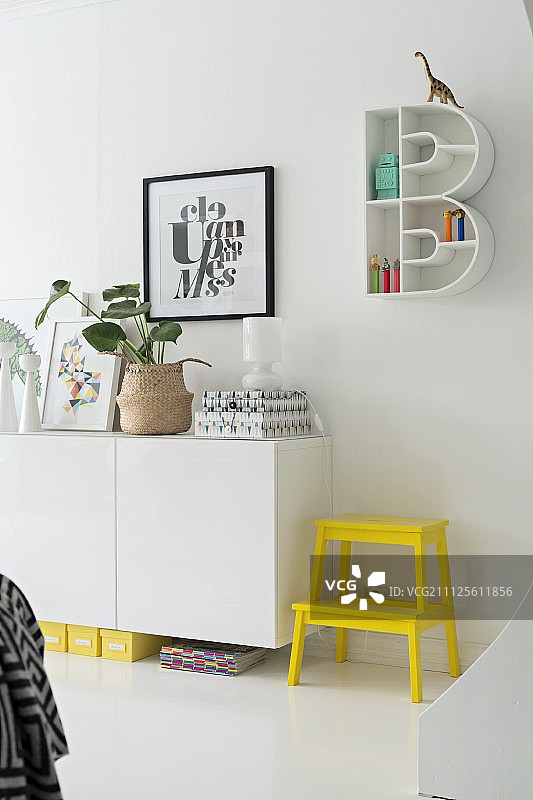 B形置物架旁侧柜旁的明黄色梯凳图片素材