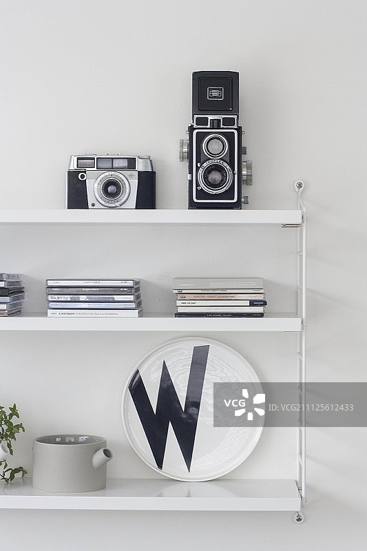 复古相机、CD盒和白色搁架上的黑白装饰盘图片素材