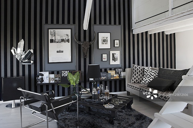 男性室内瓦西里椅与黑白沙发，灰色和黑色条纹壁纸上的 framed 图片图片素材