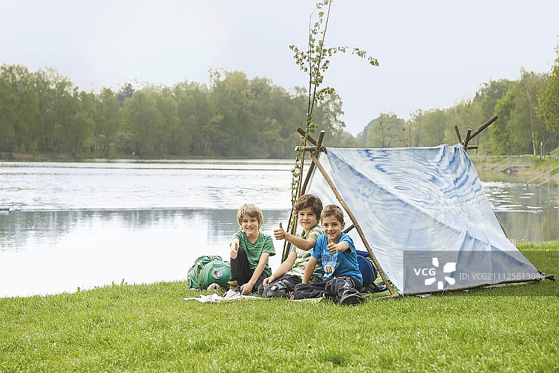 在河岸边用树枝和床单搭帐篷的儿童图片素材