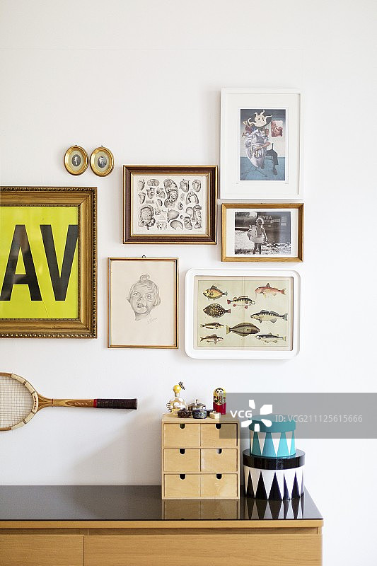 餐具柜上的微型抽屉柜和盒子，墙上挂着照片和网球拍图片素材