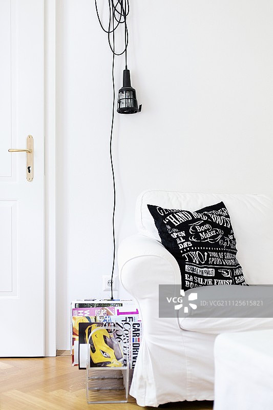 白色宽松沙发和墙上工作灯下的杂志架图片素材