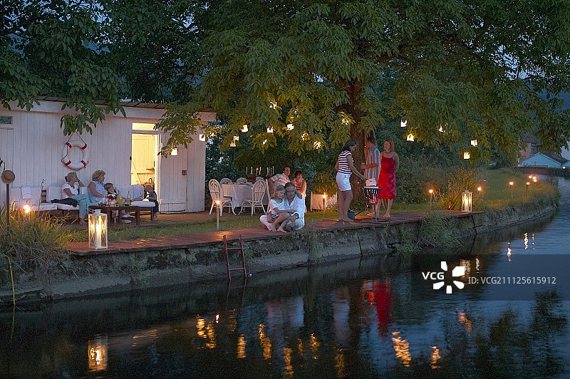 黄昏时分的浪漫花园派对：宾客在火炬和灯笼之间图片素材