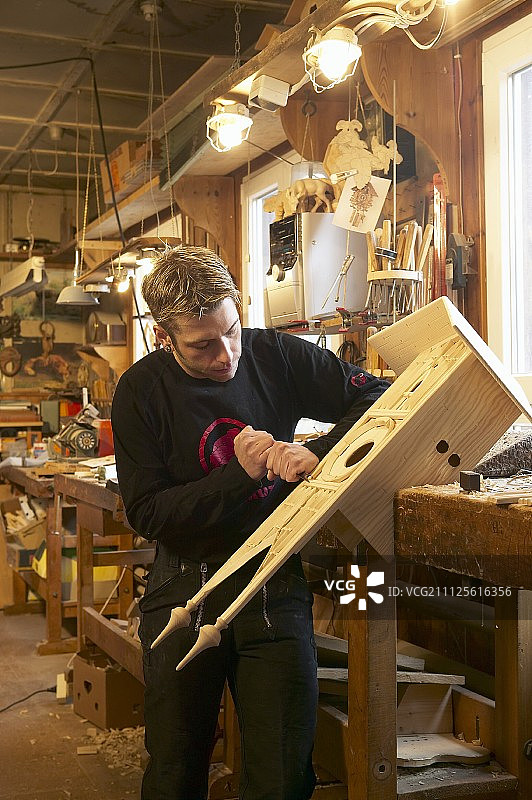 年轻的钟表匠在工作台上制作布谷鸟钟图片素材