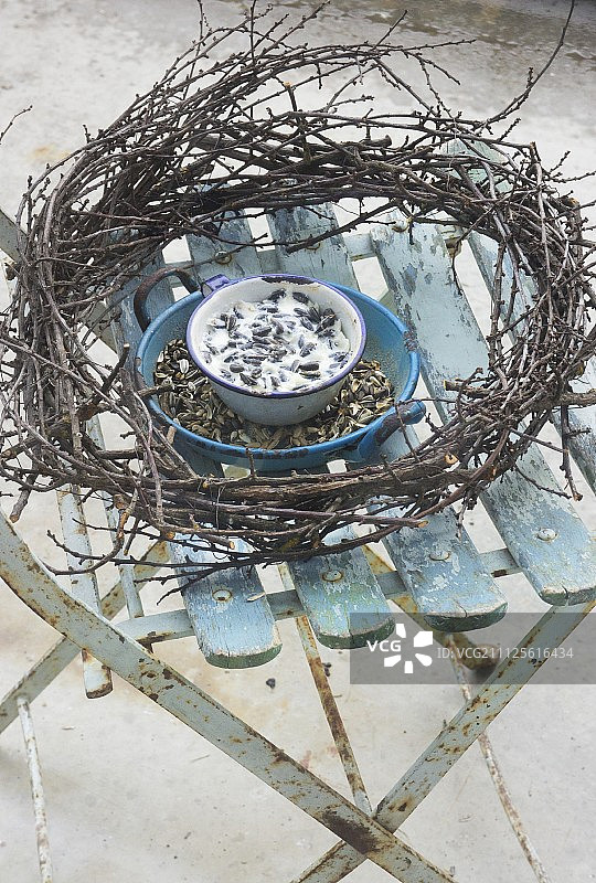 花园椅上搪瓷碗里的鸟食和树枝花环图片素材