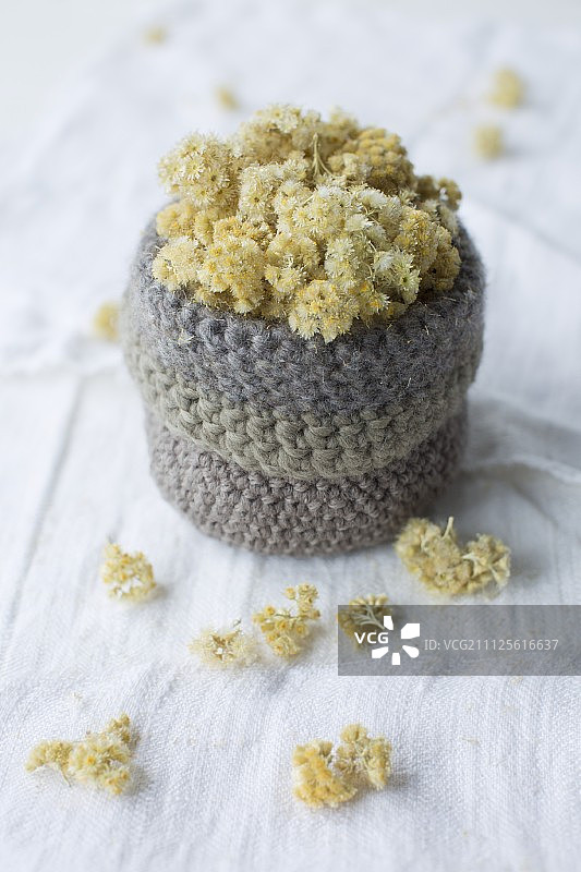 亚麻布上钩针编织篮子里的干燥永生花图片素材