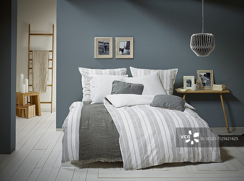 斯堪的纳维亚卧室的条纹床单和双腿床头柜图片素材