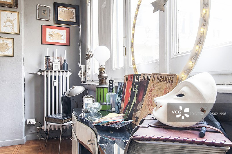 前景中的白色面具和窗前桌子上的跳蚤市场旧货图片素材