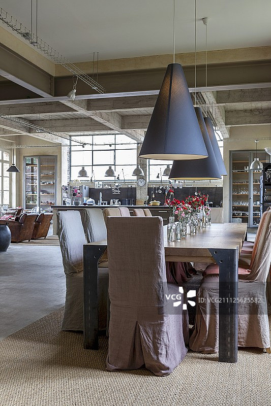 工业阁楼公寓内餐桌旁带有宽松椅套的椅子图片素材