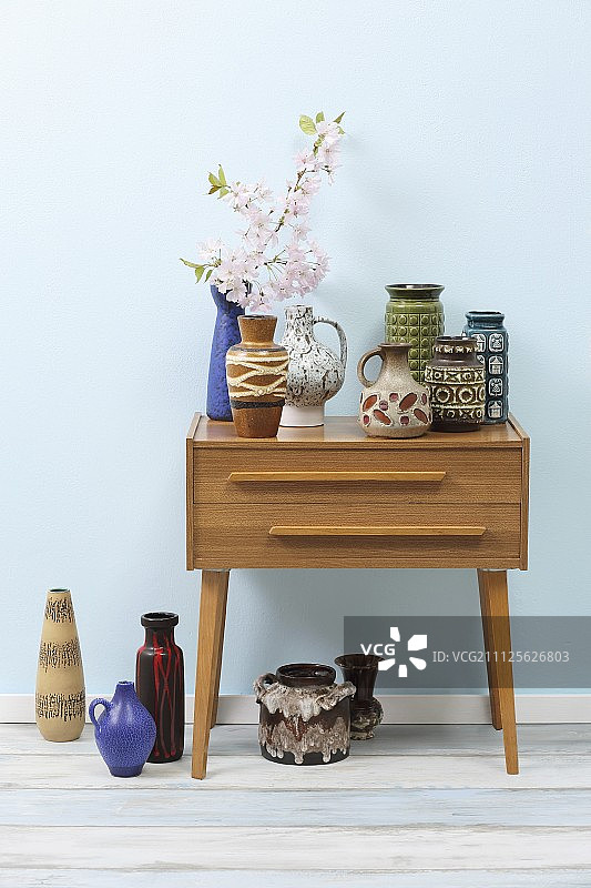 淡蓝色背景下的复古陶瓷花瓶和抽屉柜图片素材