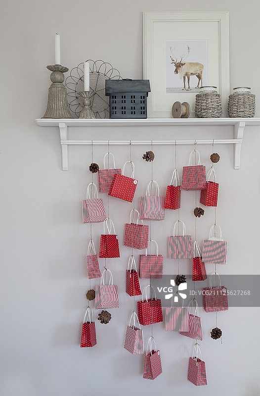 用纸袋和冷杉锥制成的降临节日历挂在墙壁式架子上图片素材