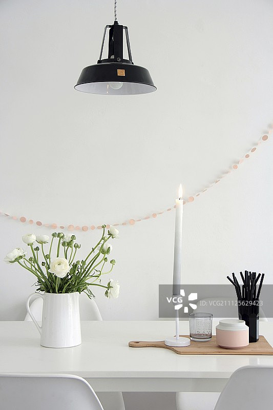 白色餐桌上的花毛茛花瓶与黑吸管图片素材