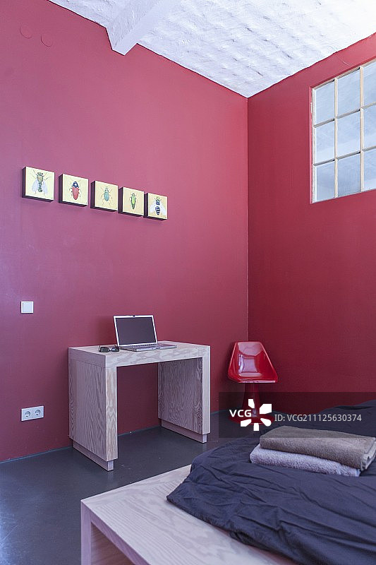 卧室角落极简主义工作区红色墙壁旁的笔记本电脑桌图片素材